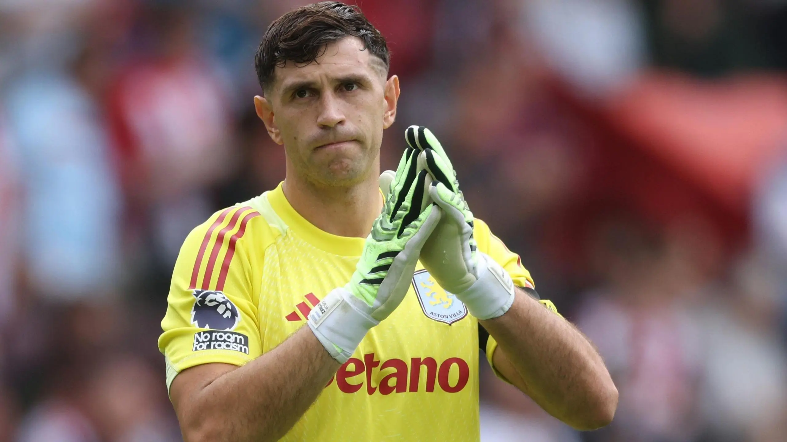 Emiliano Martinez in Aston Villa kit, applauding fans after a match.