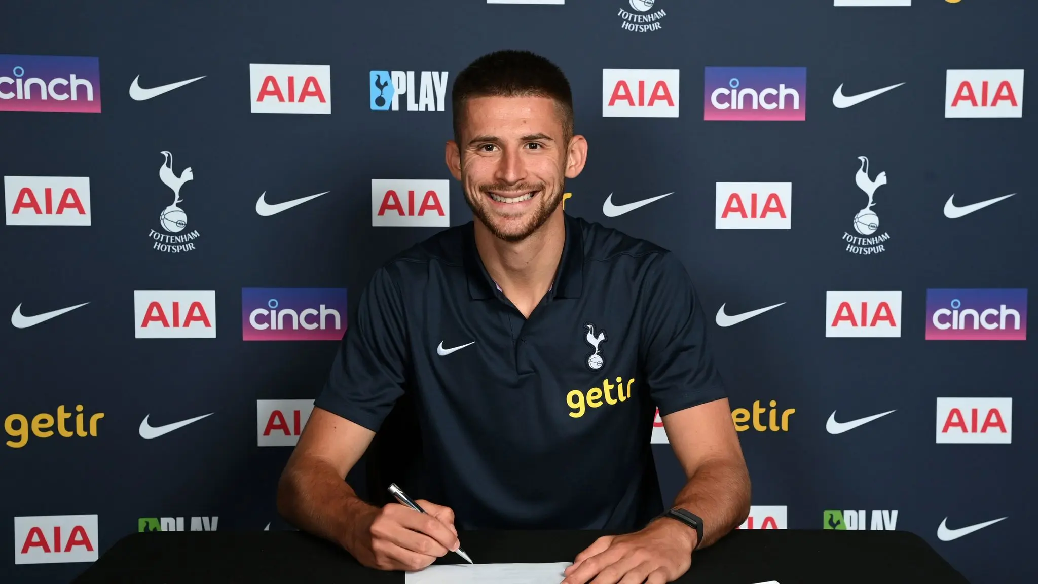 Guglielmo Vicario signing a contract at Tottenham Hotspur, wearing a club shirt.