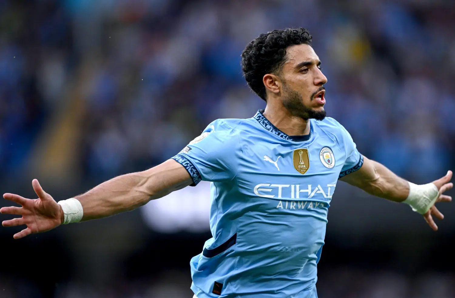 Omar Marmoush celebrating a goal in a light blue Manchester City jersey.
