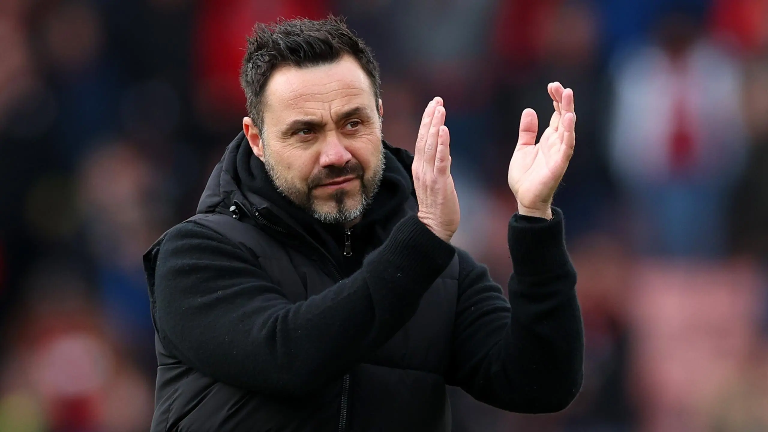 Roberto De Zerbi, football manager, clapping while wearing a black jacket.