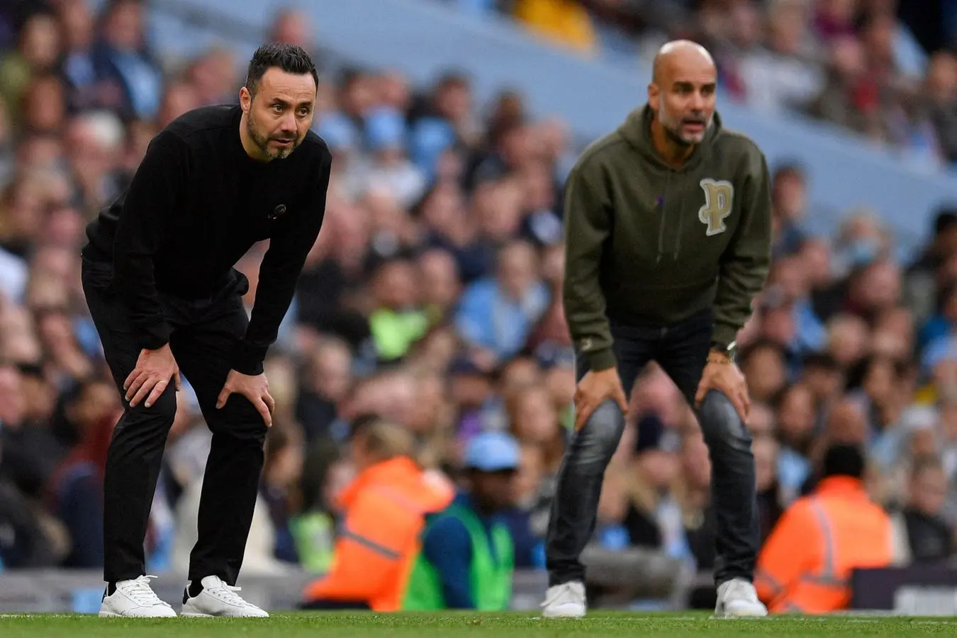 Roberto De Zerbi and Pep Guardiola standing on the sidelines during a football match.