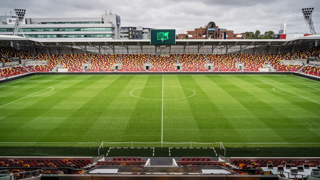 Wide shot of the pitch and red and yellow seating at the Gtech Community Stadium