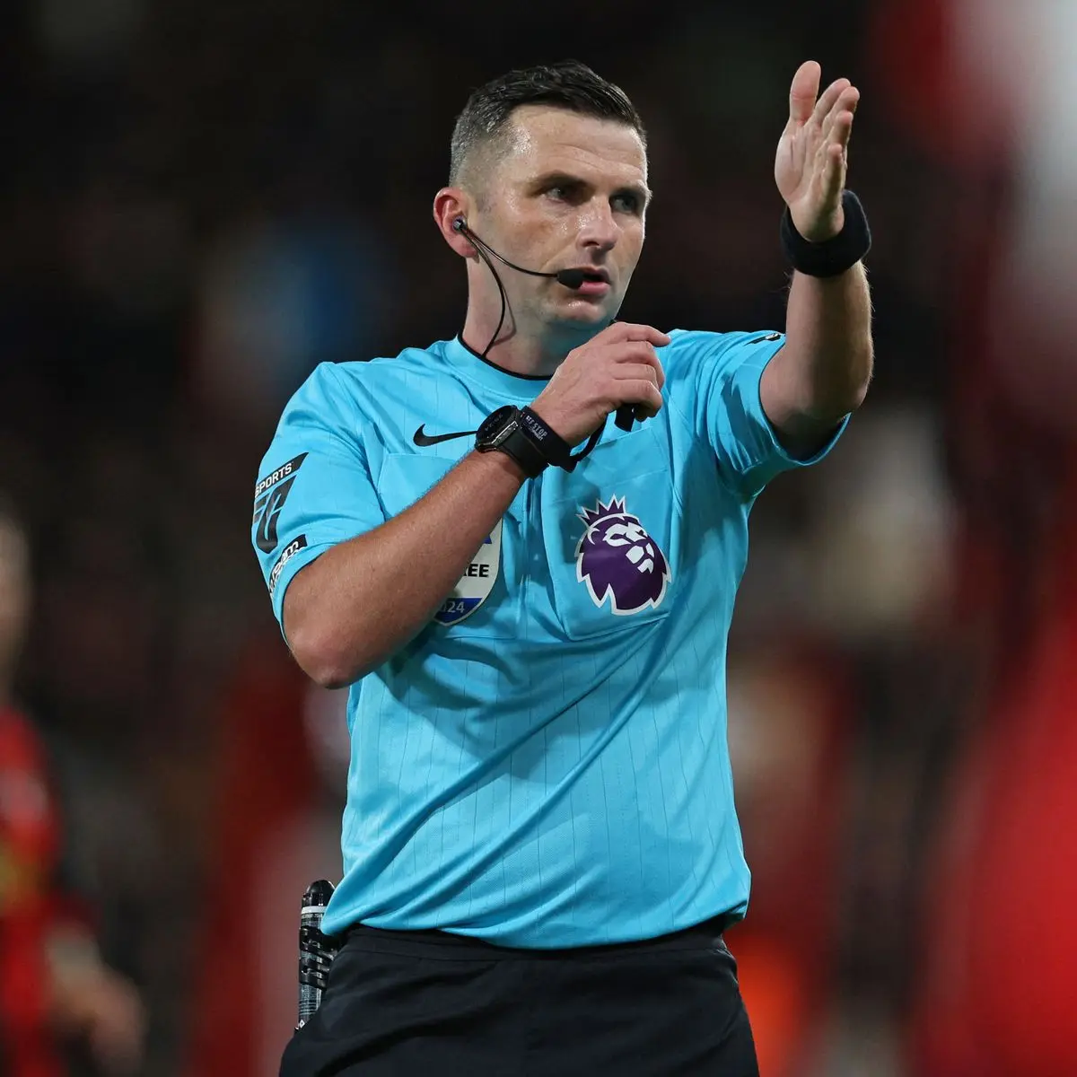 Premier League referee Michael Oliver in a light blue kit gesturing during a football match