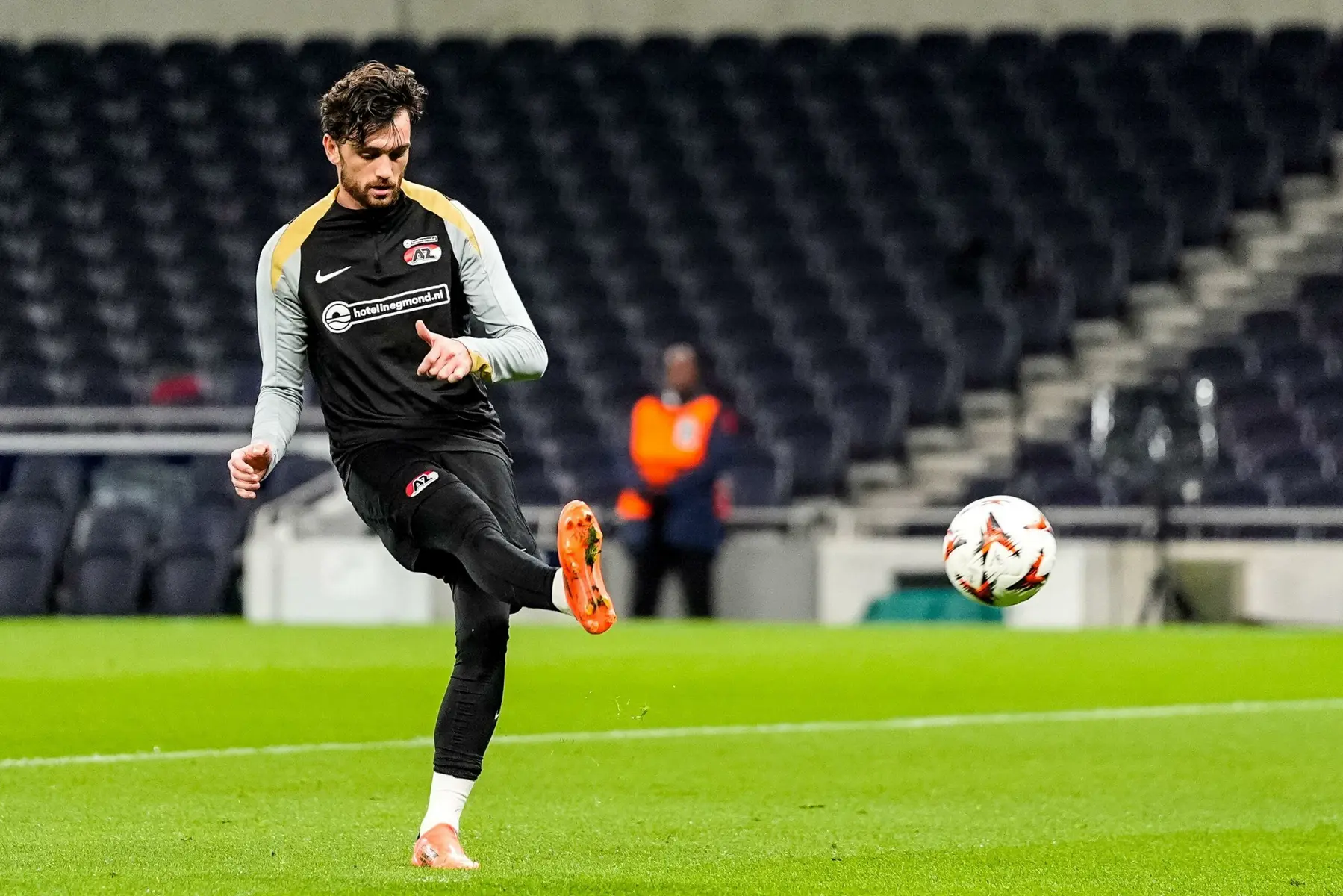 Troy Parrott in an AZ Alkmaar training kit kicking a soccer ball on a green pitch