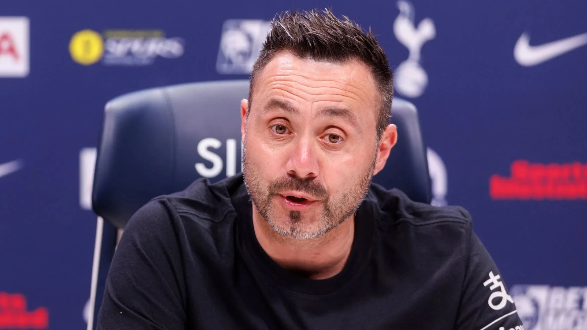 Roberto De Zerbi speaking during a press conference with Tottenham Hotspur branding in the background