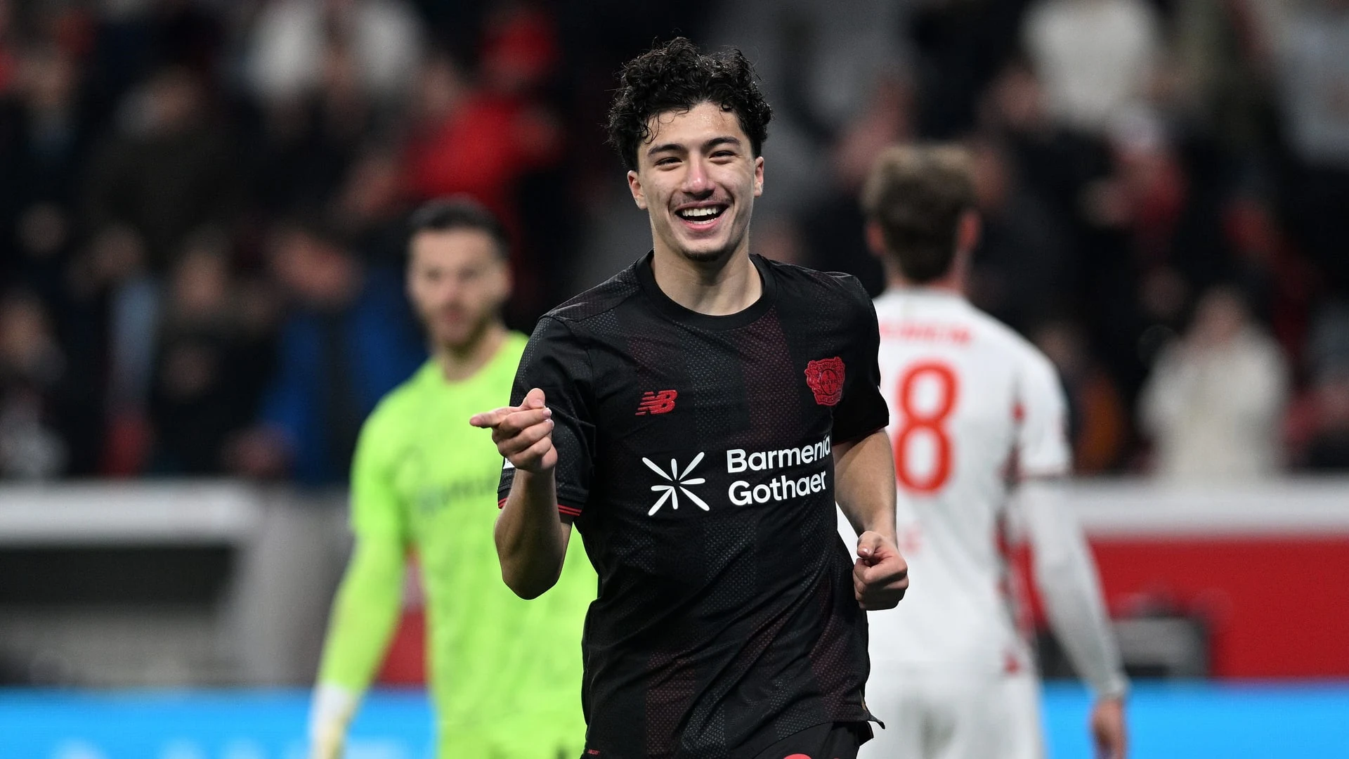 Ibrahim Maza smiling in a Bayer Leverkusen kit during a match.