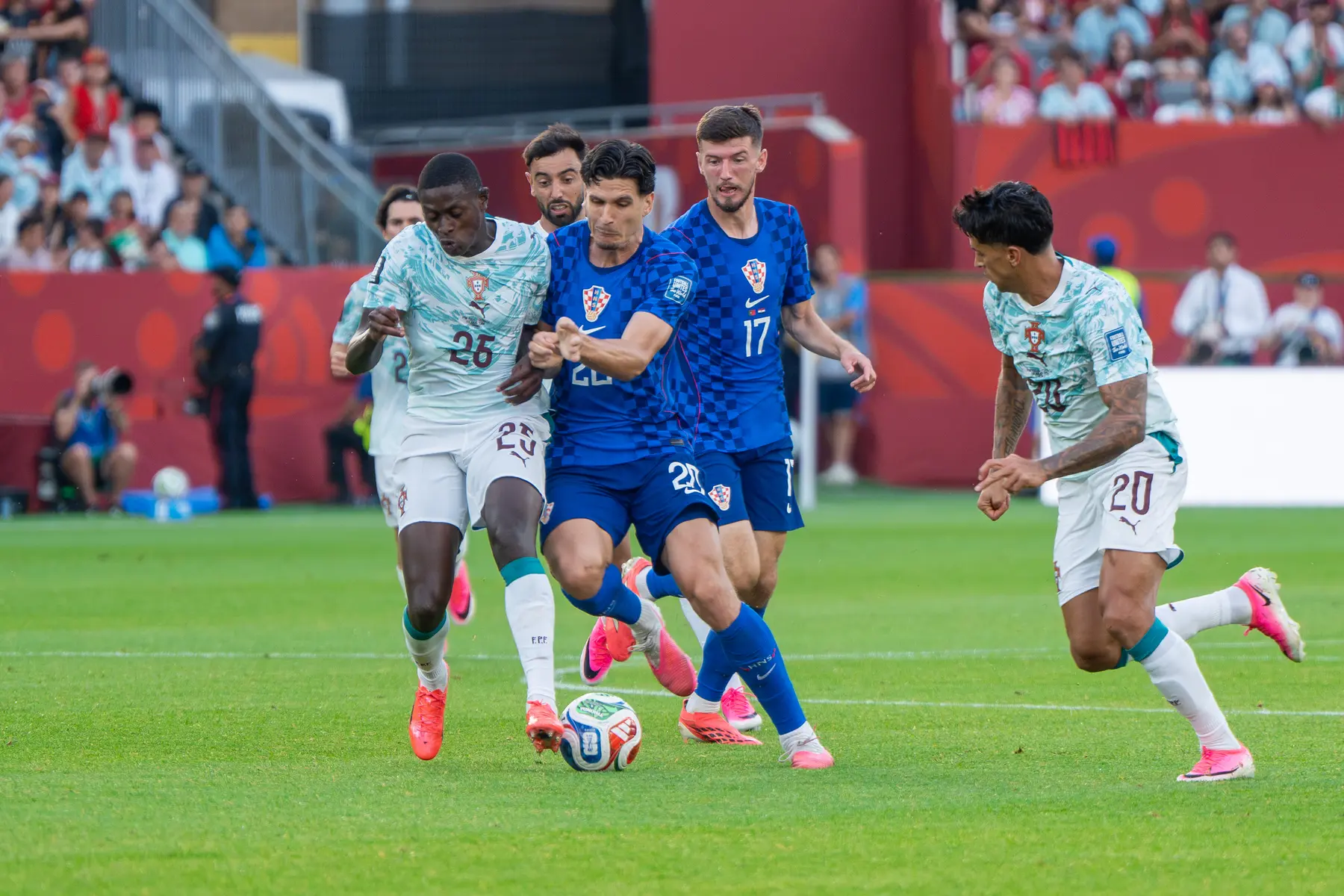 Igor Matanovic in a blue Croatia kit competing for the ball against Portugal players during a match.