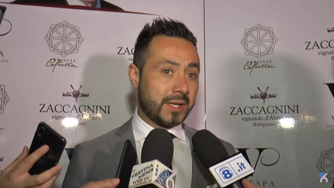Roberto De Zerbi speaking into multiple microphones during a press event.