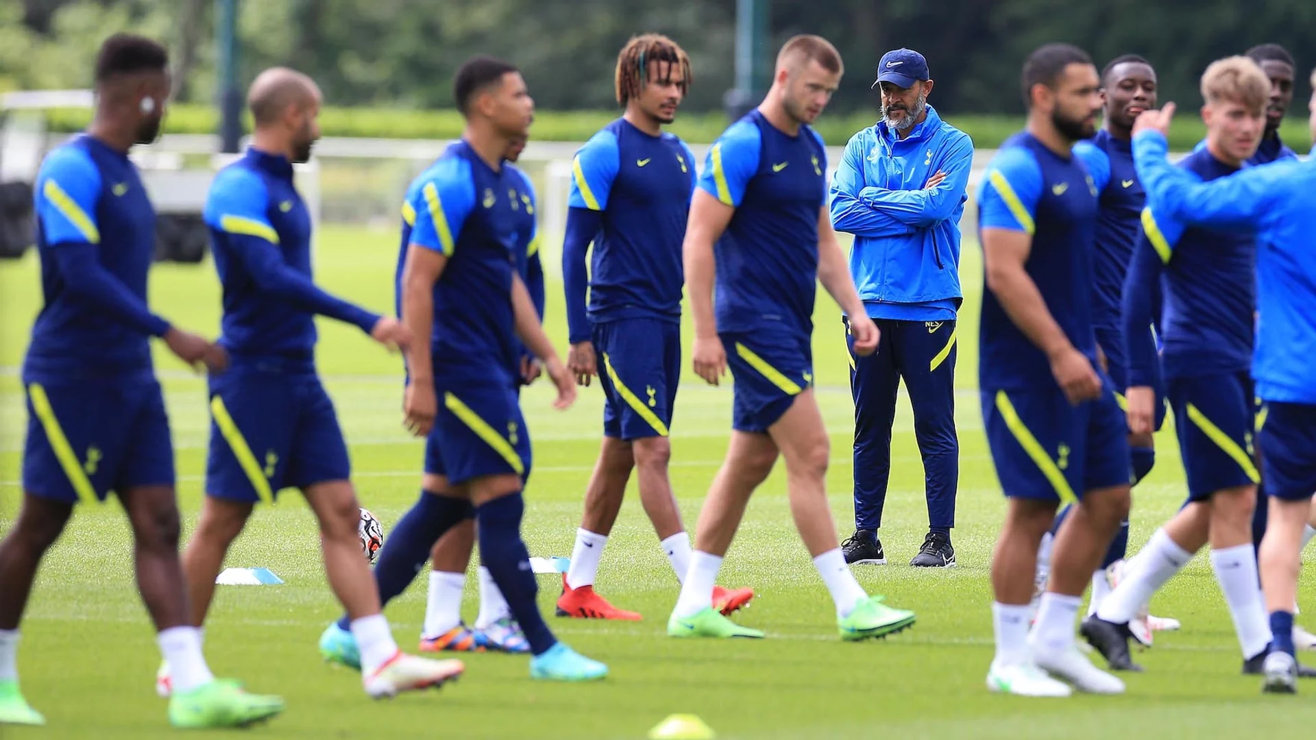 Tottenham Hotspur players and coaching staff during a training session on a grass pitch.