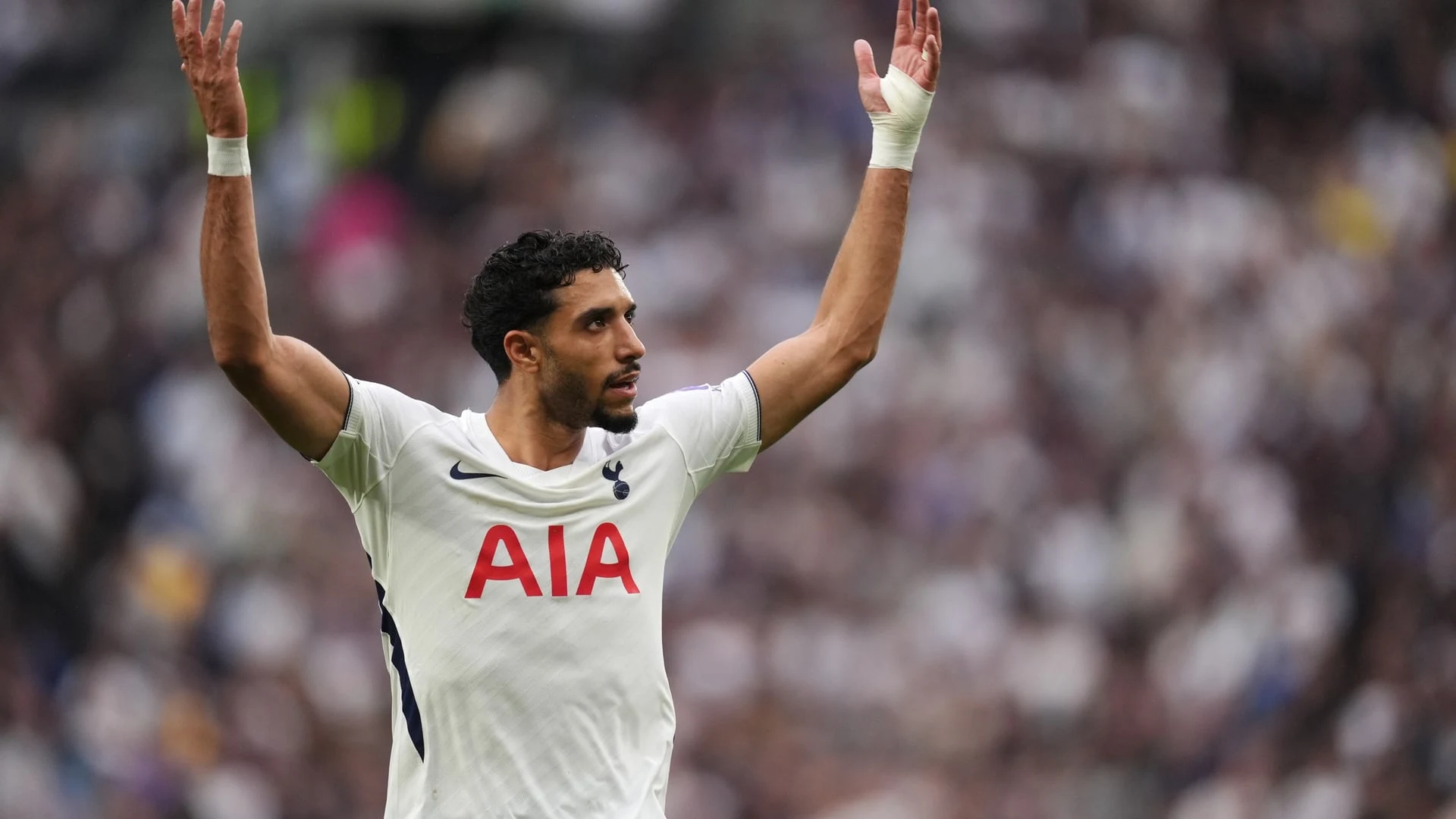 A Tottenham Hotspur player in a white kit with arms raised during a match.