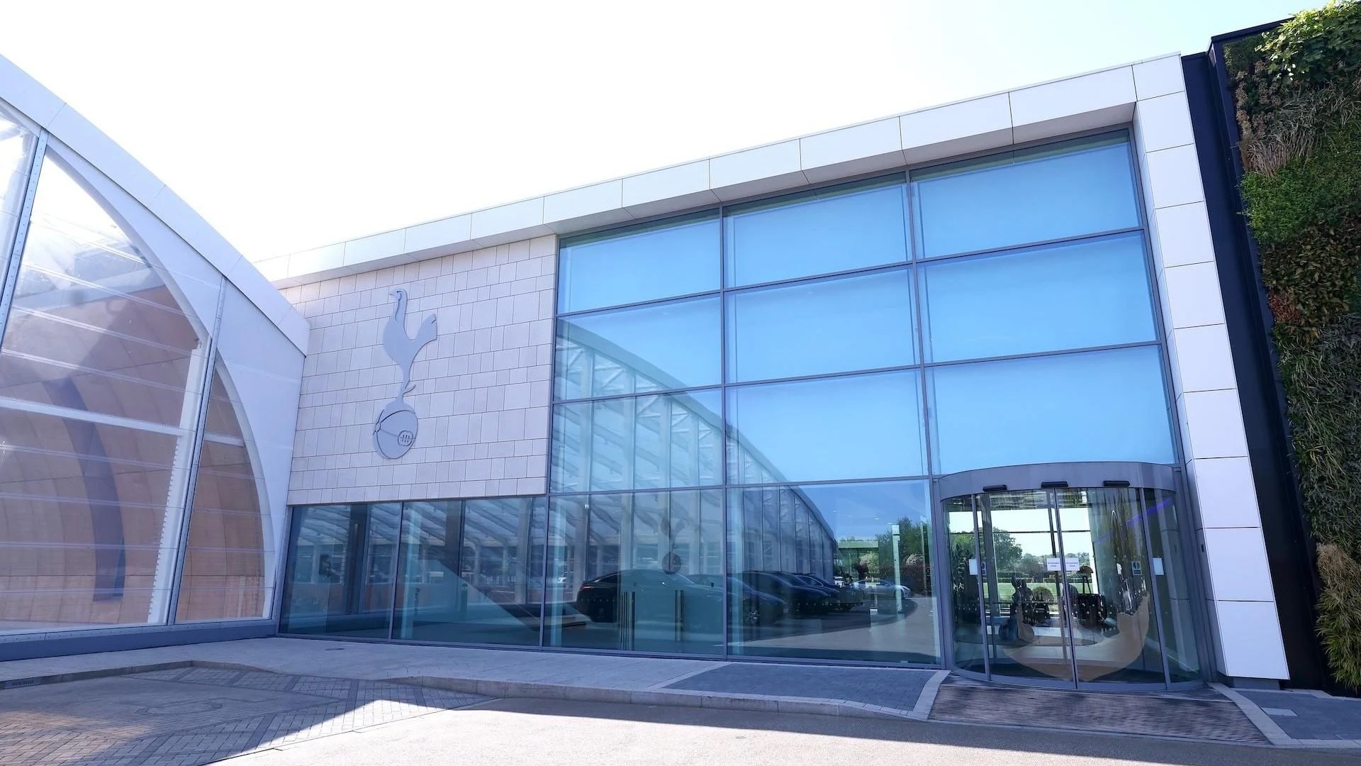 The exterior of the Tottenham Hotspur training centre building with the club crest on the wall.